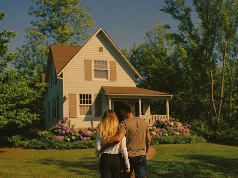 A couple walking up to a house with hydrangeas on a sunny afternoon