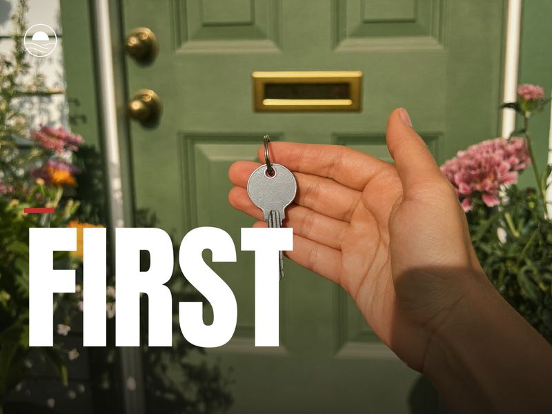 FIRST: a hand holding a house key at a green front door